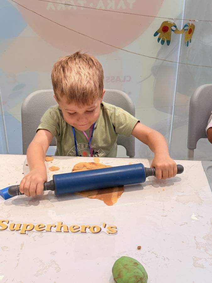 A boy rolling out dough with a rolling pin