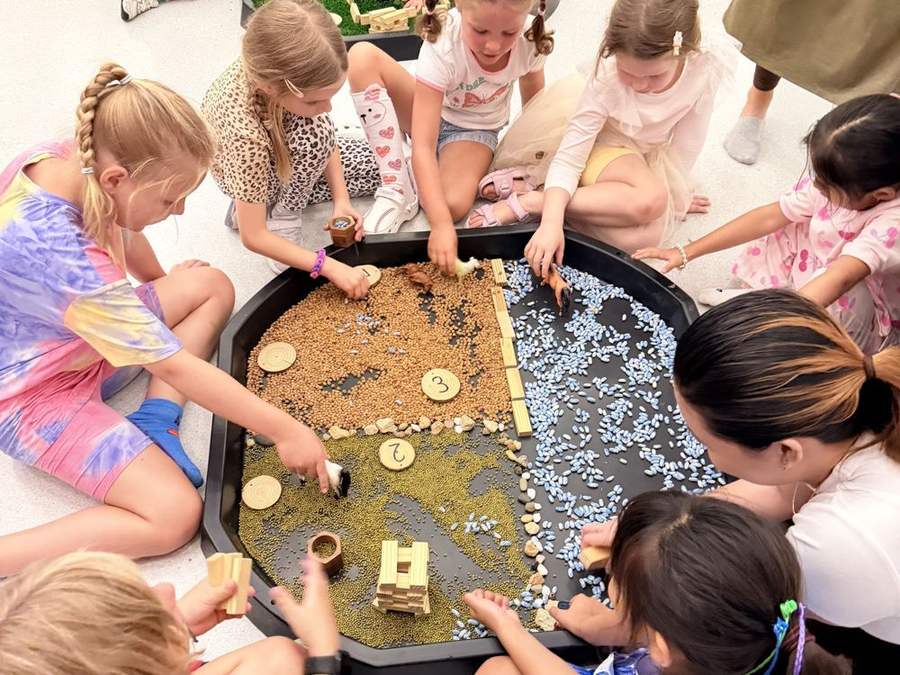 Children gathered around a sensory tray at an early years class
