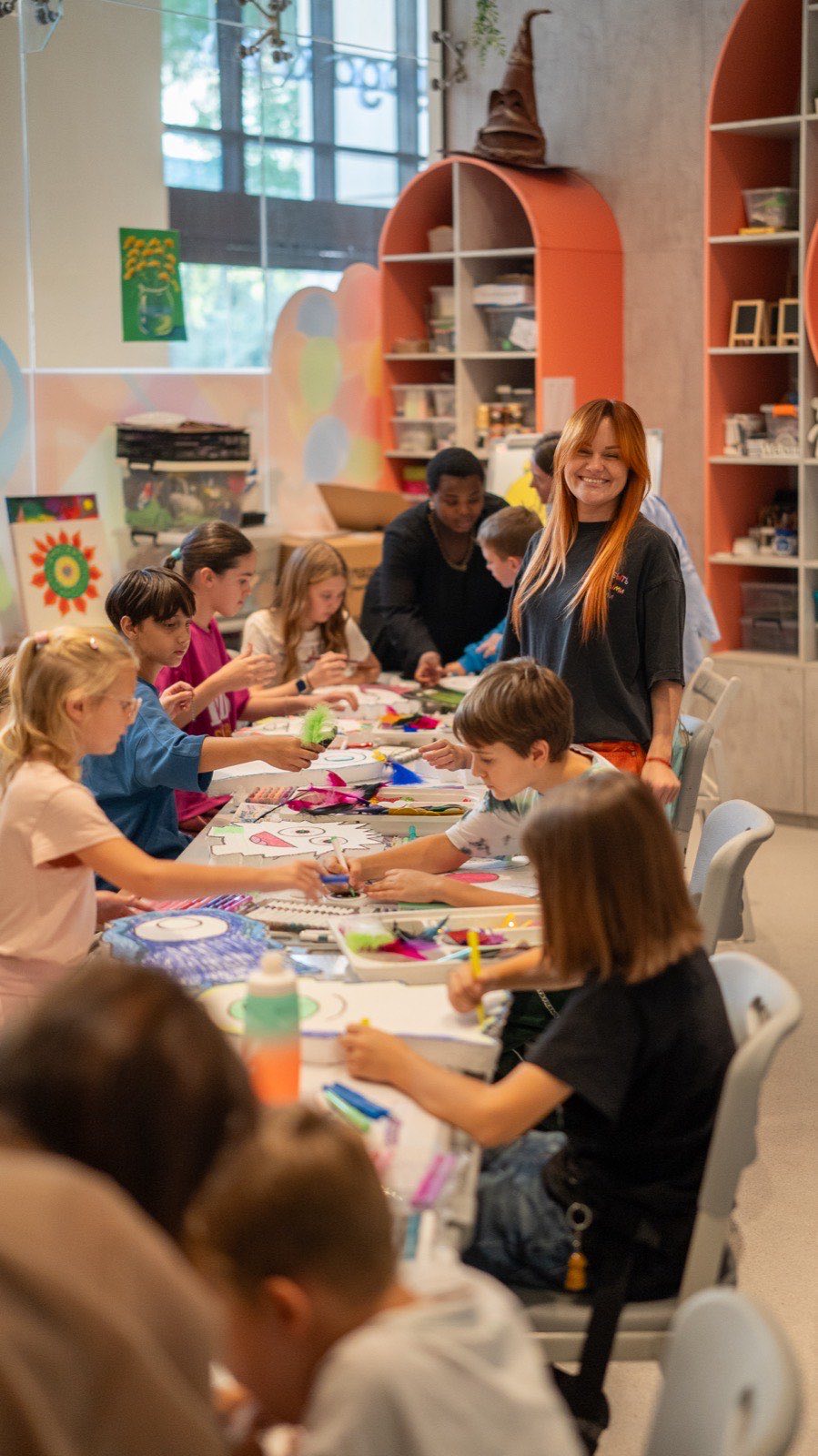 A full table of children making monsters with a teacher